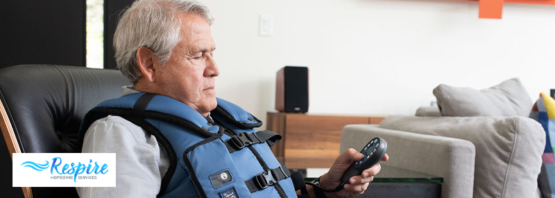 Man sitting in chair with AffloVest on him and remote in his hand