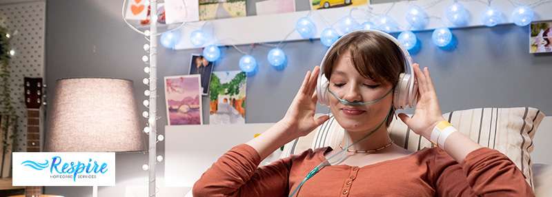 Younger lady using an oxygen concentrator while listening to music in bed