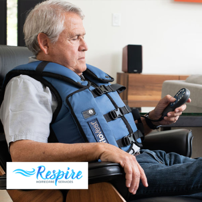 Man sitting in chair with AffloVest on him and remote in his hand