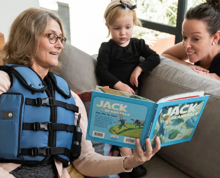 woman reading book to child with vest